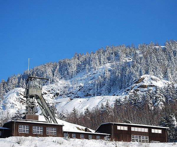Das Bergwerk Rammelsberg in Goslar liegt vor einem schneebedeckten Berg.