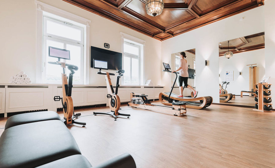 Hoher Fitnessraum mit Geräten in einem warmen natürlichen Ambiente